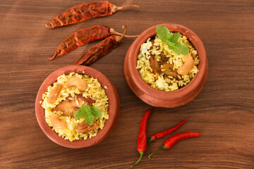 Spicy and delicious chicken biryani in traditional clay pot. Malabar biryani or Hydrabadi chicken biryani, Dum Biriyani, Chicken pulao basmati rice, herbs, raitha for Ramadan Kareem, Eid