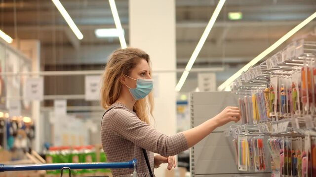 Woman Shopper Choosing Product In Hypermarket Store.Girl In Face Mask Shopping In Market On Covid19 Coronavirus Pandemic Quarantine Lockdown. Bayer In Medical Mask In Supermarket Avoid Self Distance
