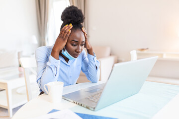 Woman sitting alone in her office and coughing as she suffers from a cold. Medical mask and hand disinfectant and stressed woman. Shot of a businesswoman working in her office while shi is sick.