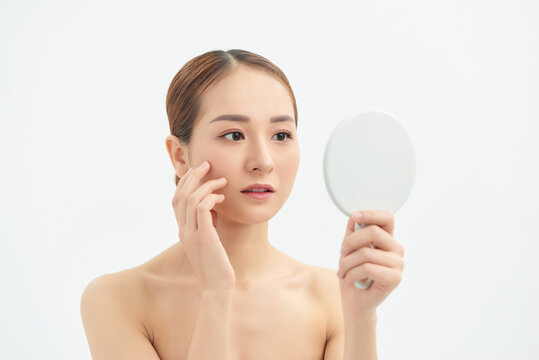 Young Asian woman with problem face looking at the mirror  over white background.
