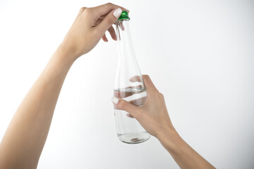 image of woman's hands holding bottle of water on isolated white background