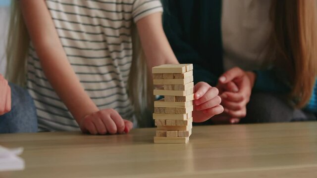 Young family plays jenga at home, enjoying their relationships, spending weekend together at home, strengthen family bonds, Foreground, Slow motion.