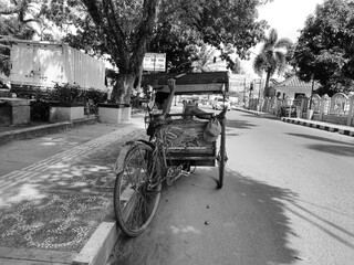 Fototapeta na wymiar Palembang - Indonesia, 06/16/2020: portrait of a traditional Indonesian rickshaw driver in an environmentally friendly vehicle