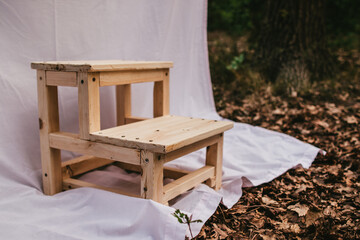 Small wooden staircase-stool on a light cloth in the forest