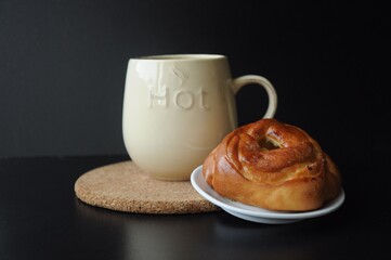 Bun on a saucer and a mug with the inscription 