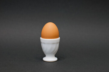 chicken egg in eggcup on a black background. natural protein. ingredients for sports nutrition.