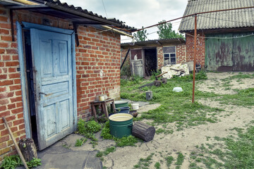 Naklejka premium Poor rural residential courtyard with brick buildings in Ukraine. The concept of life in the Ukrainian village, a simple old dwelling