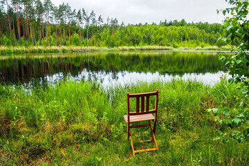 Folding chair on the shore of a beautiful lake in summer