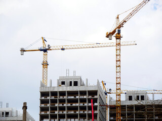 Construction site with crane and building. Two cranes near building under construction.
