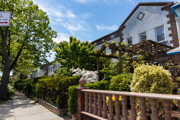 Fototapeta na wymiar Beautiful Spring Sidewalk Scene with Old Homes and Green Gardens in Astoria Queens New York
