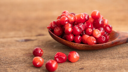 Cranberry placed in a wooden spoon and placed on a wooden floor,  Red sour fruit  There are many health benefits.