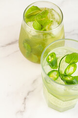 green cocktails with ice and mint on a white background.