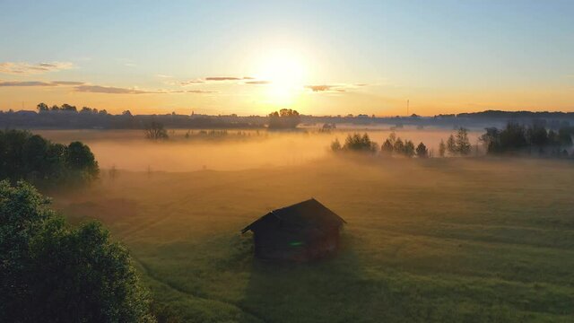 Fog morning over the plain and river floodplain of the meadow near a rural village with a house, aerial view landscape