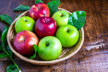 .Green apple and red apple in a basket on a wooden background