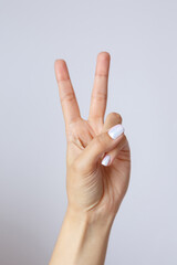 Gesture and sign, female hand on a white background. Fingers showing peace or victory