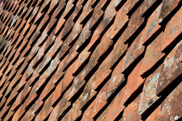 Roofing material texture. Antique tiled roof. Natural slate roof tiles cover the house. Close-up of a diamond-shaped tile imitating fish scales