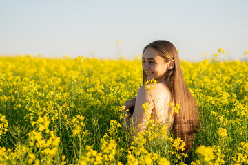 Naklejka na ściany i meble Beautiful girl in a rapeseed field, with an open shoulder.