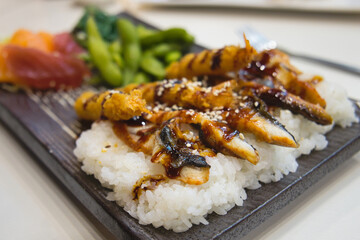 Delicious Asian dinner - boiled rice with grilled fish fillet, soy sauce and vegetables 