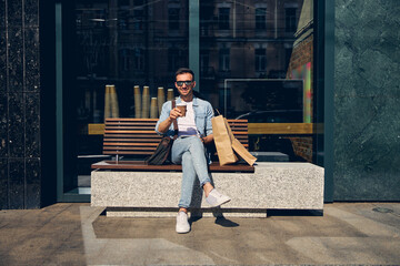 Delighted brunette man sitting outside near business center