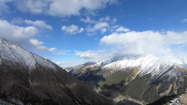 4k timelapse video of the current of clouds and changing weather in the mountains in spring green gorge and snow-capped mountain tops