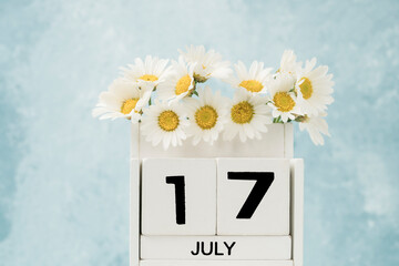 White cube calendar for july decorated with daisy flowers