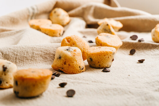 Several little Chocolate chips muffins with some chocolate chips and muffins on the background. Tasty and sweet concept.