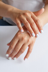 Obraz na płótnie Canvas Woman applying moisturizer to her hands. Hand skin care. Health and beauty concept