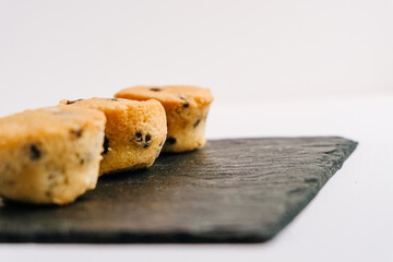 Chocolate chips little muffins in a dark slate board plate isolated on white. Selective focus. Muffin, sweet and food concept.