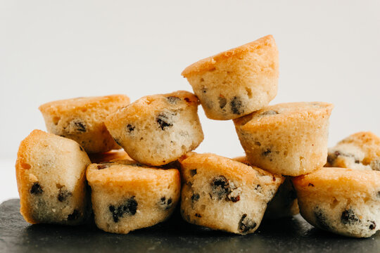 Chocolate chips little muffins in a dark slate board plate isolated on white close up view. Muffin, sweet and food concept.