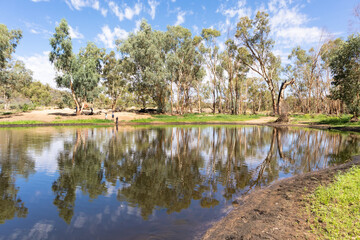 Fototapeta na wymiar Trees and people reflected on a water pond. Perfect symmetry. Ellery Creek Big Hole, West Macdonnell ranges, Northern Territory NT, Australia, Oceania