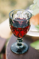 There’s a glass of red wine on the wedding table..A vintage glass of wine caught in the sun. .