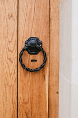 Black metal round handle on a light wooden door