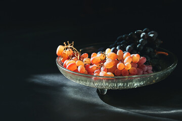 Blue and pink grape illuminated by sun, on a black background, top view