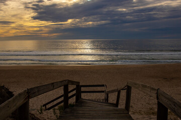 Fototapeta premium View of empty beach and part of wooden handrail at sunset a few minutes before dark. Quiaios beach, Portugal.