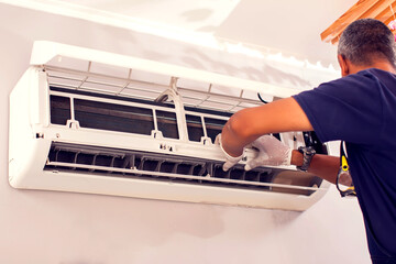 Man worker fixing air conditioning on the wall. - obrazy, fototapety, plakaty