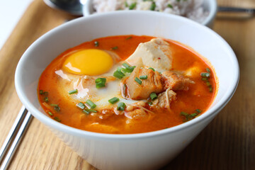 Korean soft tofu kimchi soup served with riceberry rice on a wooden tray placed on a white table Ready to eat