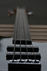 Fototapeta na wymiar Das Griffbrett einer schwarze E Bass Gitarre von unten fotografiert und auf dem Seitenhalter fokussiert. Man sieht die ganze länge der Seiten und des Griffbretts und ein Teil des Korpus.