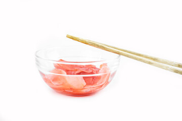 eating pickled ginger in transparent bowl with chopsticks on a white background