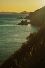 Summer sea landscape at sunset with rocks and hills in the background, toning.