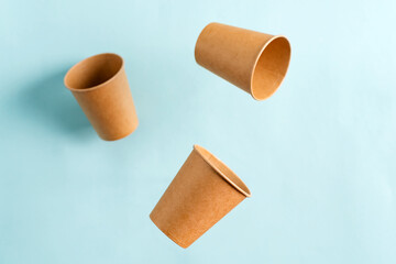 Flying eco friendly paper disposable mockup cups above pastel blue background. Zero Waste