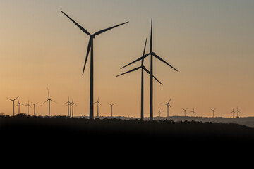 Obraz premium Black Silhouette of windturbines energy generator on amazing sunset at a wind farm in germany