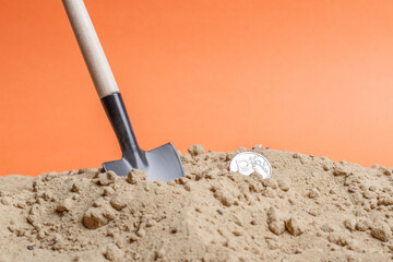 miniature shovel in the sand near the Russian ruble coin