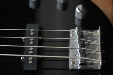 Der Seitenhalter von einer schwarze E Gitarren Bass von oben und sehr nah fotografiert. Man sieht nur ein Teil der Seiten, ein Knopf und ein Teil des Korpus..