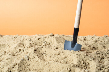 shovel stuck in the sand on an orange background