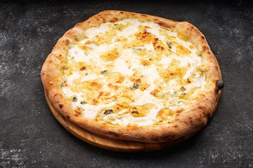 Four cheese pizza on a light wooden board, on a dark concrete background