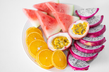 White plate of sliced fruit. Fresh fruits and vitamins. Still life colored summer fruits.