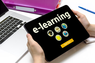 Tablet in den Händen eines Kindes mit dem weißen Text E-LEARNING vor einem Schreibtisch mit...