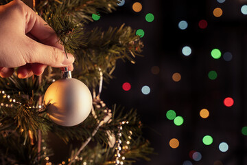Christmas background concept- beautiful decor bauble hanging on the Christmas tree with sparkling light spot, blurry dark black background, copy space, close up.
