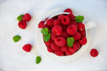 Fresh raspberries with leaves in white cup
