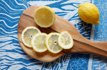 Lemon slices on wooden cutting board on a blue textile background